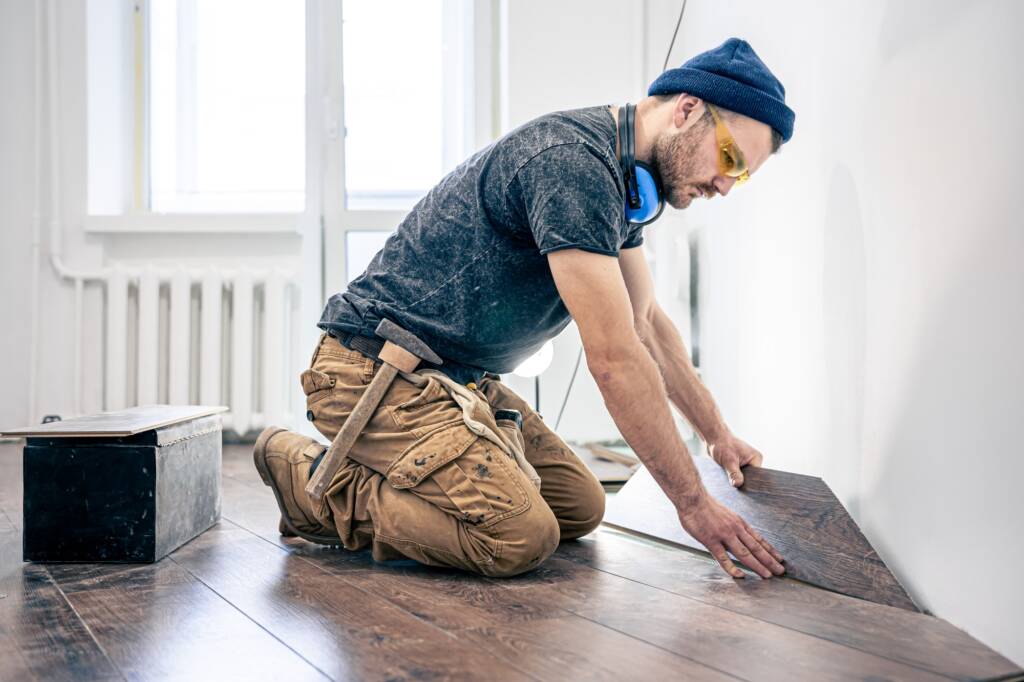 A male worker puts laminate flooring on the floor.